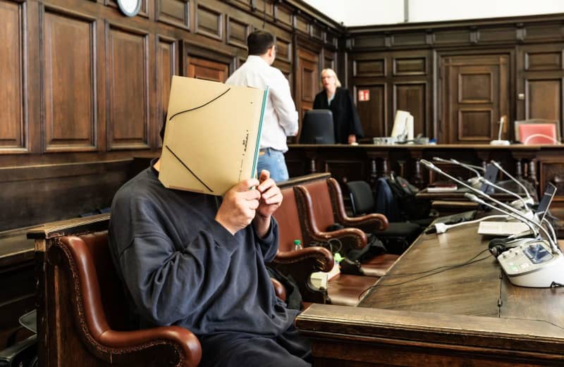 The defendant hides his face in the courtroom. The trial before the Higher Regional Court is about war crimes committed by a Syrian government militia between 2012 and 2015. The accused is a 47-year-old Syrian who entered Germany in February 2016 and was arrested in Bremen on August 2023. Markus Scholz/dpa-Pool/dpa