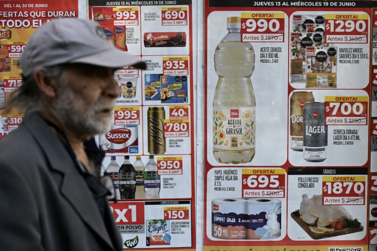 A man walks past food price signs on a street in Buenos Aires on June 13, 2024 (LUIS ROBAYO)
