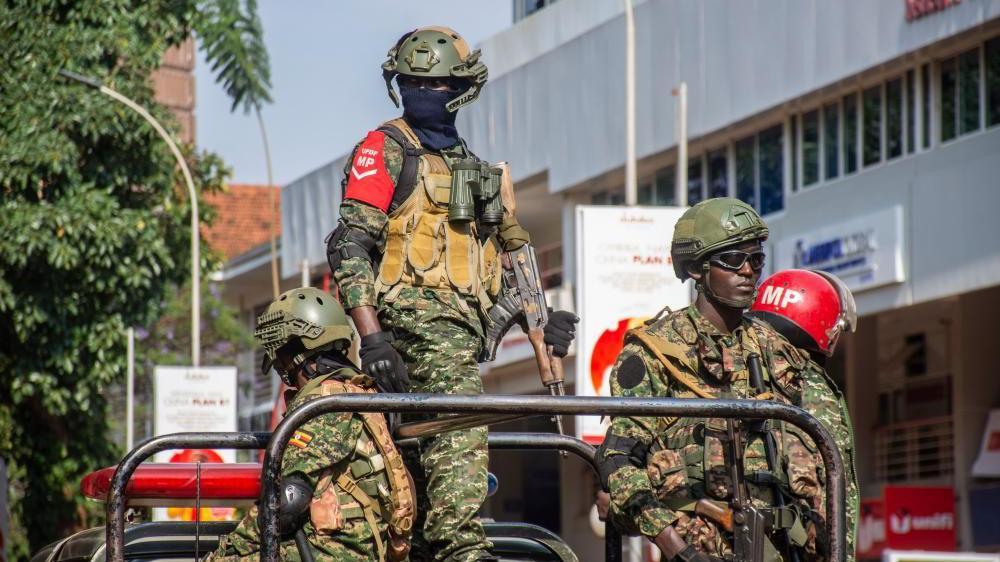 Members of Ugandan security forces stand guard outside the Uganda Parliament during an anti-corruption march in Kampala, Uganda, 23 July 2024. Four men in soldiers uniforms are seen stood on the back of a truck.