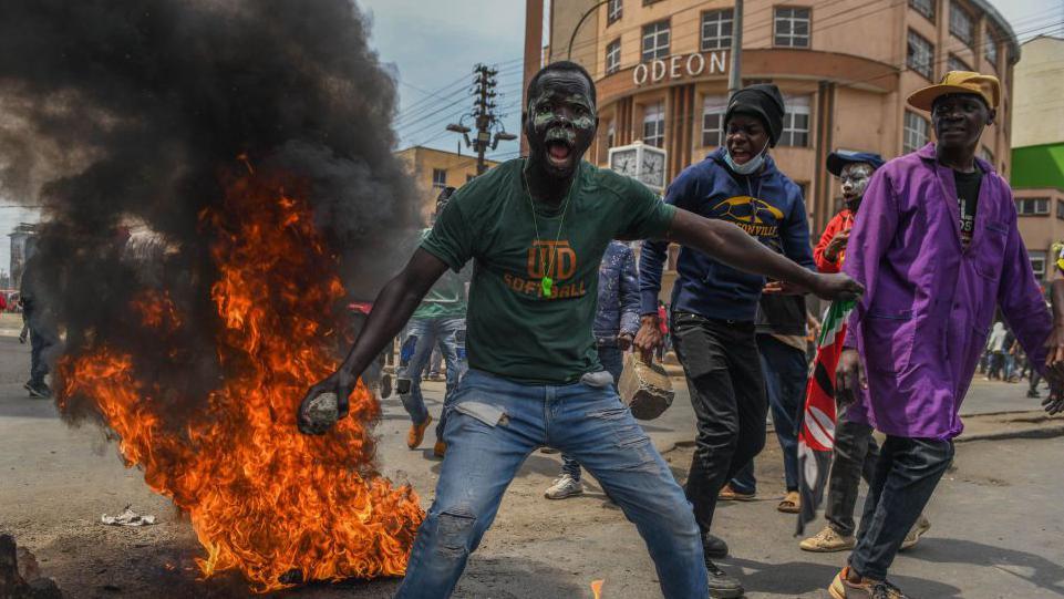 Demonstrators, gathering in the city center, make a fire as they march towards the parliament building to protest the 'Finance Bill 202