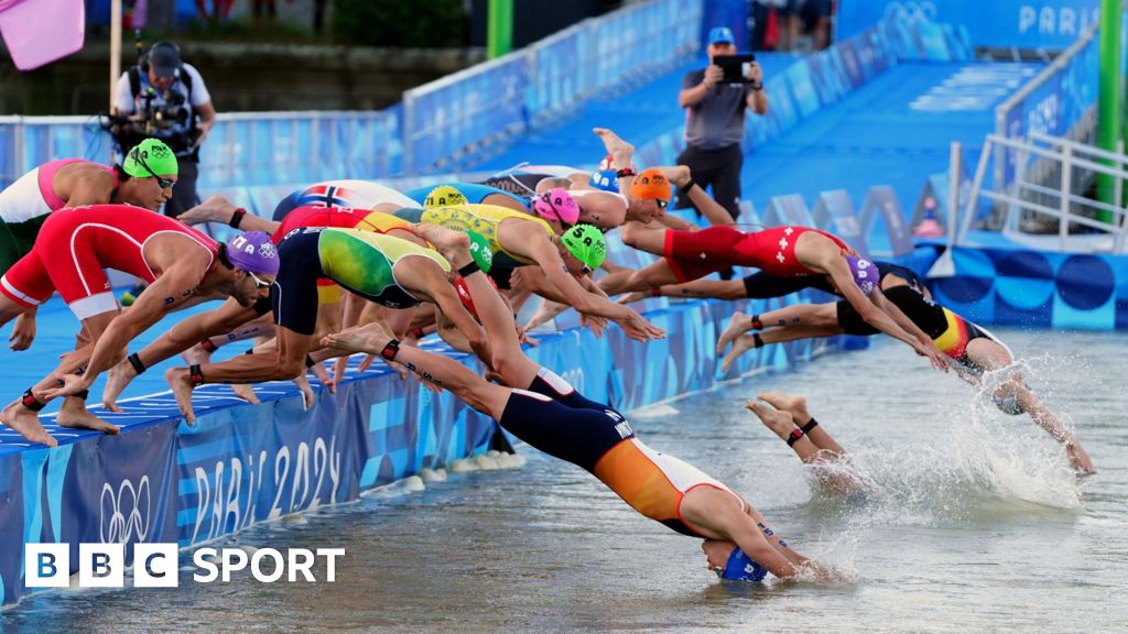 Triathletes dive into the River Seine at the start of the mixed team relay at the Paris 2024 Olympics