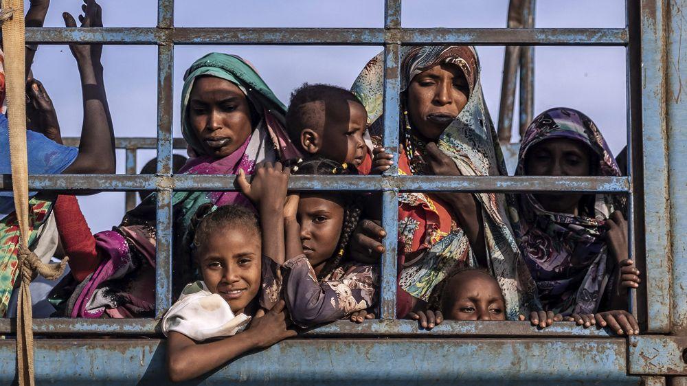 Sudanese refugees and South Sudanese returnees who have fled from the war in Sudan stand on a truck arriving at a Transit Centre for refugees in Renk, on February 13, 2024