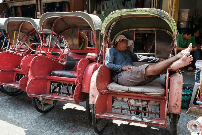 The driver of an Indonesian bechak, a traditional pedicap, sleeps in front of a market in Surakarta, Central Java. The economy of the country cooled slightly in the second quarter of 2024, according to latest data (YASUYOSHI CHIBA)