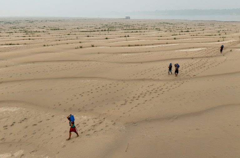 People carry drinking water along a sandbank of Madeira River in Paraizinho Community, in Humaita, Amazonas state, northern Brazil, on September 7, 2024 (MICHAEL DANTAS)