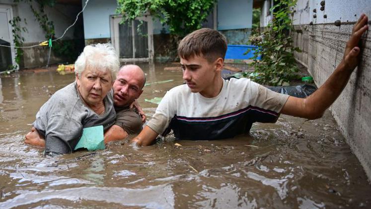 Local residents rescue an elderly man (C) from the rising flood waters in the Romanian village of Slobozia Conachi, 14  September 2024.