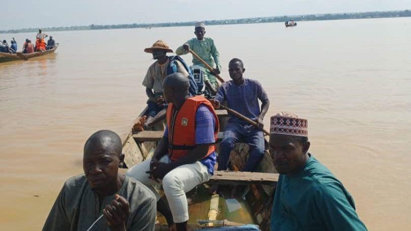 Divers and local volunteers on a rowboat in the River Niger