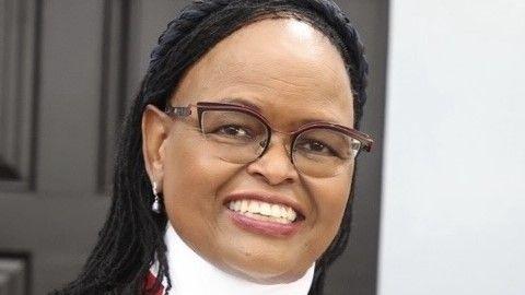 Profile picture of Chief Justice Koome in her office within Kenya’s Supreme Court. She is wearing glasses and smiling.