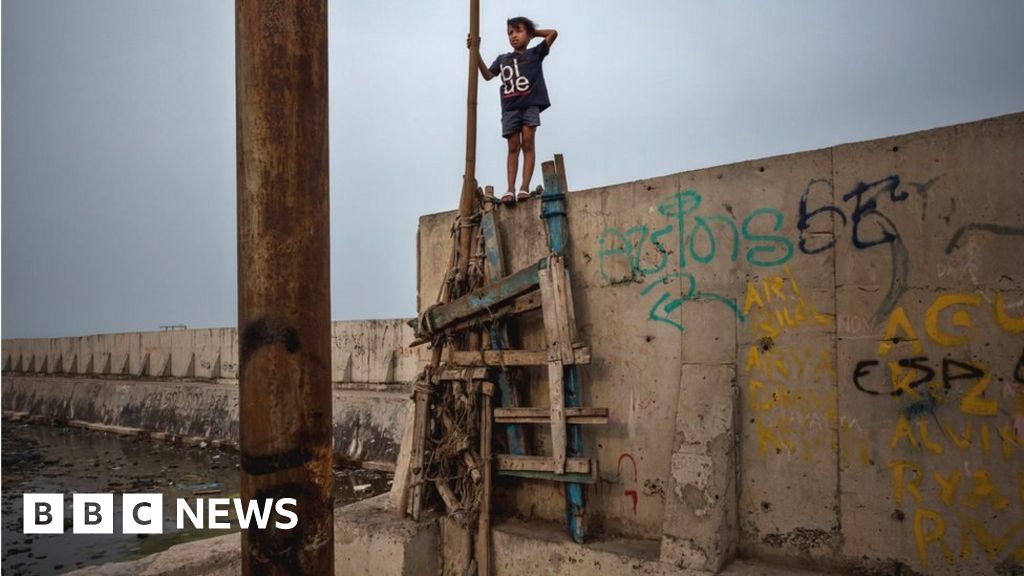 A boy walks on the newly built sea wall that protects Jakarta from the rising sea levels