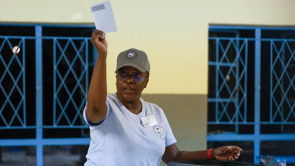 An election official holds up a ballot paper to inspect it.