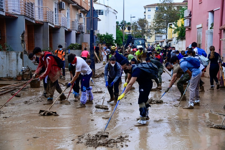 People clear mud from a street in Alfafar in the region of Valencia, eastern Spain (JOSE JORDAN)