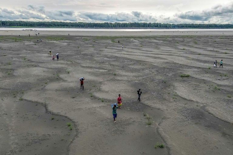 Yagua Indigenous people carry water and other goods due to the low level of the Amazon river at Isla de los Micos in Colombia (Luis ACOSTA)